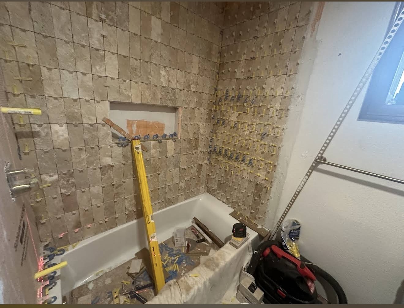 During — stone tile installation in progress with leveling clips.