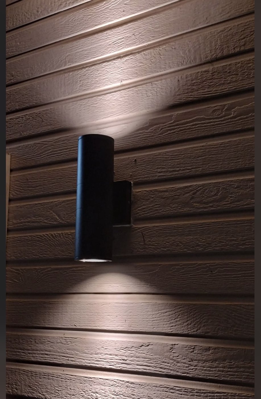 Exterior LED cylinder sconce light fixture installation on wood siding — Stockton exterior lighting by Cazares